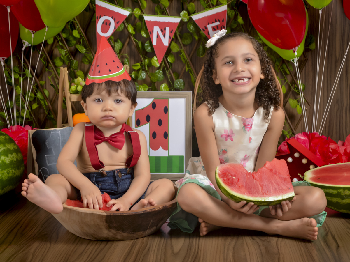 sentado na gamela com a irmã-Smash the Fruit-fruta-melancia-suspensório vermelho-gravata borboleta-ensaio infantil-gamela-one-crianças-book-acompanhamento mensal-Kids-foto em estúdio-Newborn-Fotografa de família-Drica Studio-fotografa  em Xinguara-Pará.