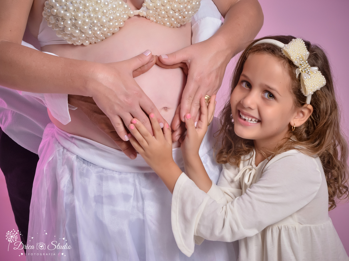 Família em ensaio no estúdio-mão na barriga- fazendo coração com as mãos-alegres fundo rora-mãe e pai e irmã-muito amor na gestação-gravidiva-coroa de flor na cabeça-fotógrafa de família-fotógrafa-Drica Studio Fotografia Xinguara-Pará.
