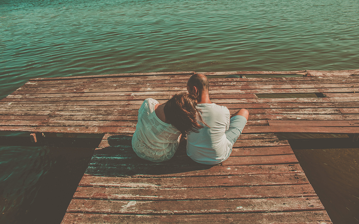 casal sentado de costas no deck