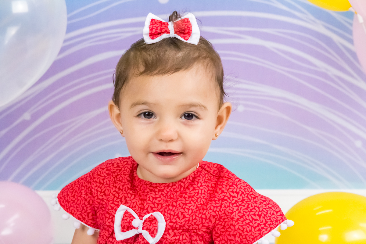 MENINA sentada de VESTIDO VERMELHO olhando para a CÂMERA no click da FOTÓGRAFA de ENSAIO SMASH THE CAKE em SÃO PAULO, SP sorridente em uma imagem colorida