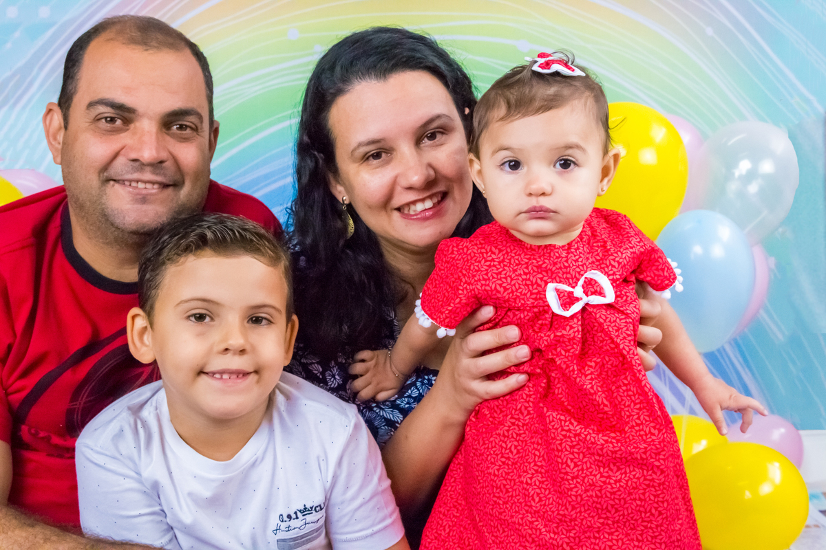 FAMÍLIA sentada olhando para a CÂMERA no click da FOTÓGRAFA de ENSAIO SMASH THE CAKE em SÃO PAULO, SP sorridente em uma imagem colorida