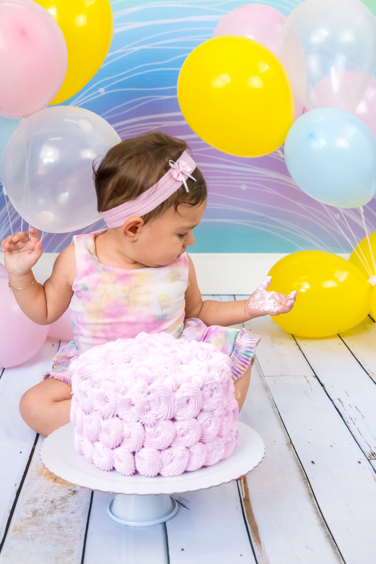 MENINA sentada AMASSANDO O BOLO olhando para a MÃO no click da FOTÓGRAFA de ENSAIO SMASH THE CAKE em SÃO PAULO, SP sorridente em uma imagem colorida