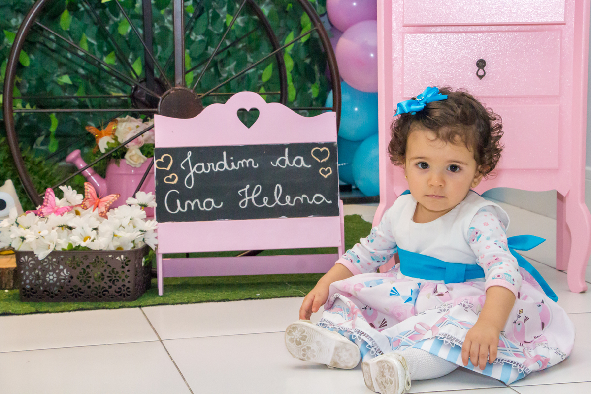 MENINA sentada de vestido com LAÇO AZUL em festa tema JARDIM ENCANTADO nas cores VERDE e CORES PASTÉIS no click da FOTÓGRAFA de FESTA INFANTIL em SÃO PAULO, SP em uma imagem colorida