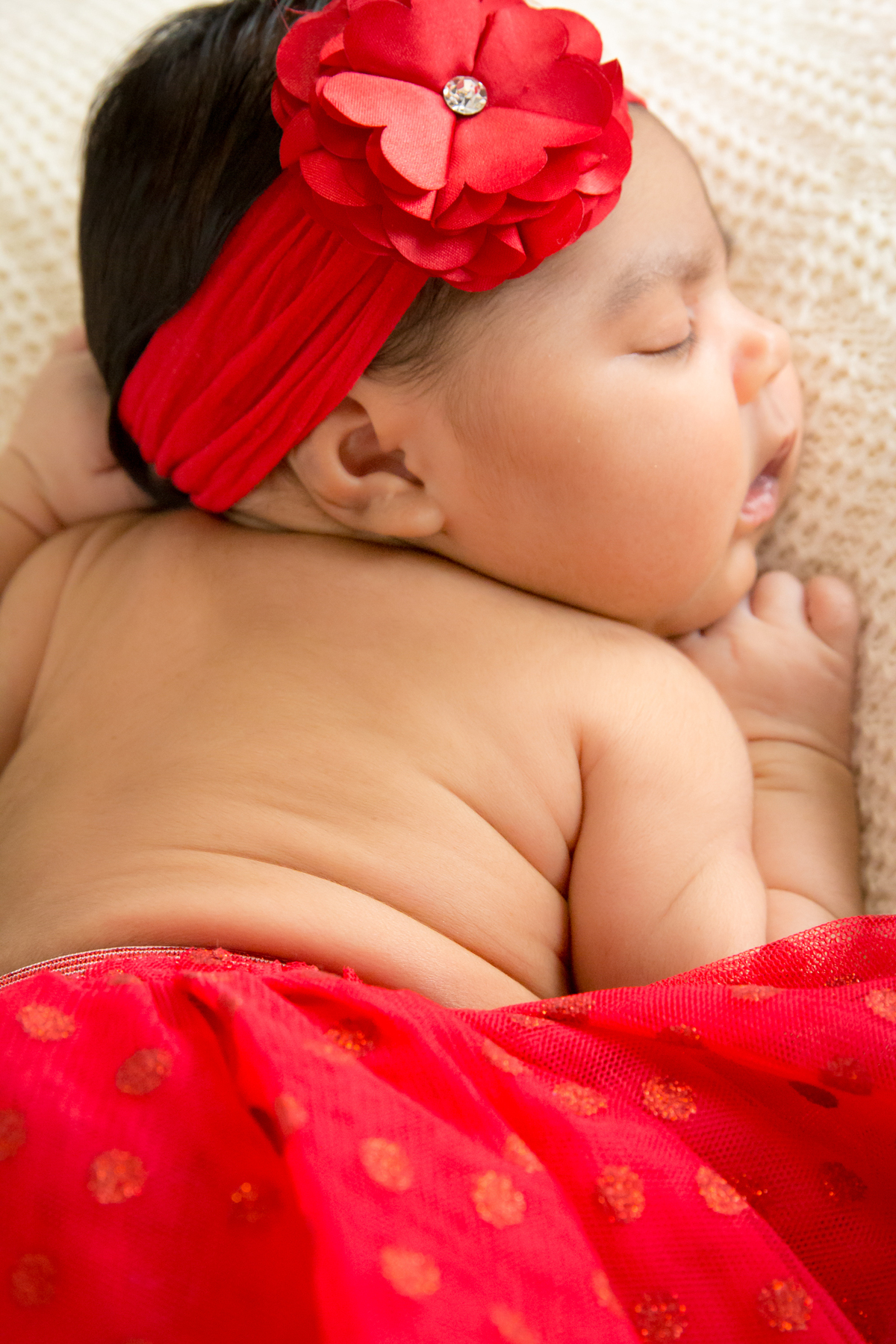 BEBÊ deitada em MANTA BRANCA dormindo RECÉM NASCIDA com SAIA VERMELHA no click da FOTÓGRAFA de FAMÍLIA e NEWBORN em OSASCO, SP em uma imagem colorida