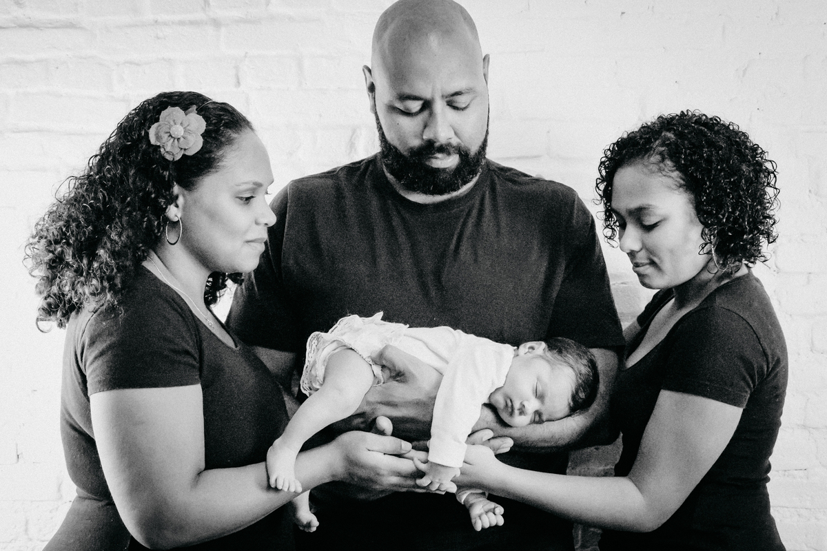 FAMÍLIA segurando BEBÊ dormindo RECÉM NASCIDA no click da FOTÓGRAFA de FAMÍLIA e NEWBORN em OSASCO, SP em uma imagem pb