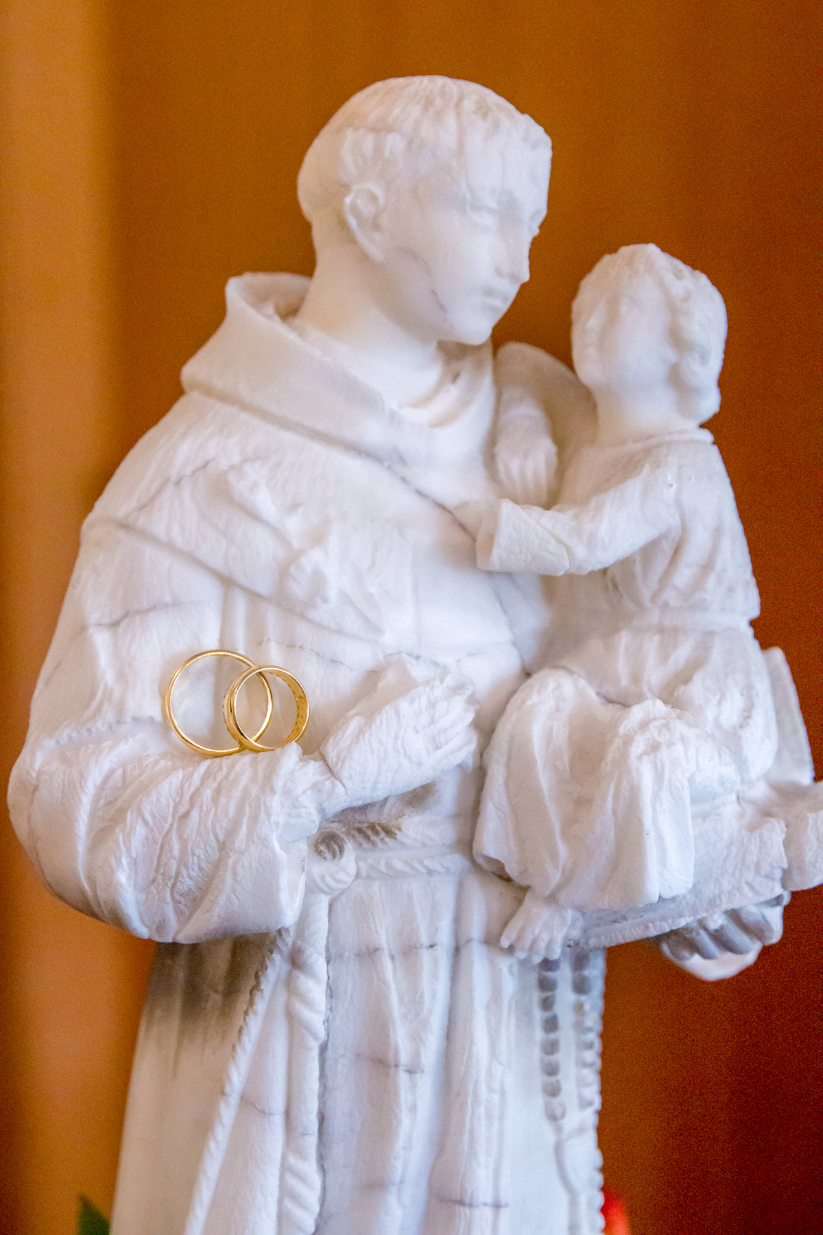ALIANÇAS nos braços de SANTO ANTÔNIO na casa dos NOIVOS no click da FOTÓGRAFA de CASAMENTO em SÃO PAULO, SP em uma imagem colorida