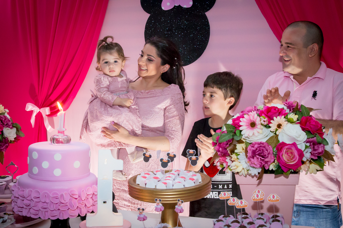 MENINA com a FAMÍLIA em CANTANDO PARABÉNS frente a decoração tema MINNIE nas cores ROSA e BRANCO no click do FOTÓGRAFO de FESTA INFANTIL em SÃO PAULO, SP em uma imagem colorida