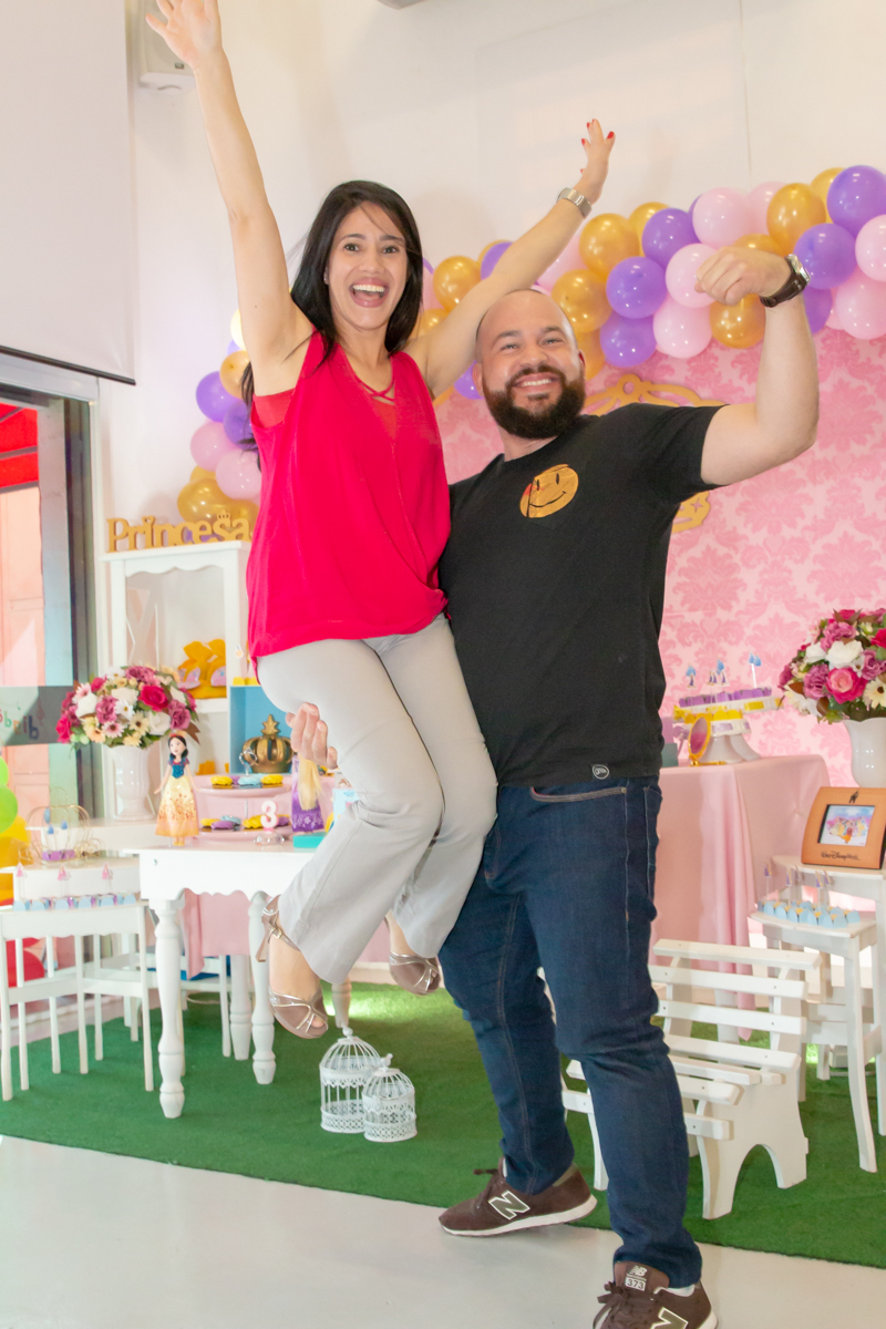 MENINA sorrindo de VESTIDO AZUL abraçada com os PAIS em frente a decoração tema PRINCESAS nas cores ROSA, DOURADO e LILÁS no click do FOTÓGRAFO de FESTA INFANTIL em SÃO PAULO, SP em uma imagem colorida