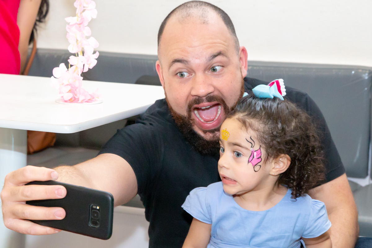 MENINA sorrindo de VESTIDO AZUL brincando com PAI no click do FOTÓGRAFO de FESTA INFANTIL em SÃO PAULO, SP em uma imagem colorida
