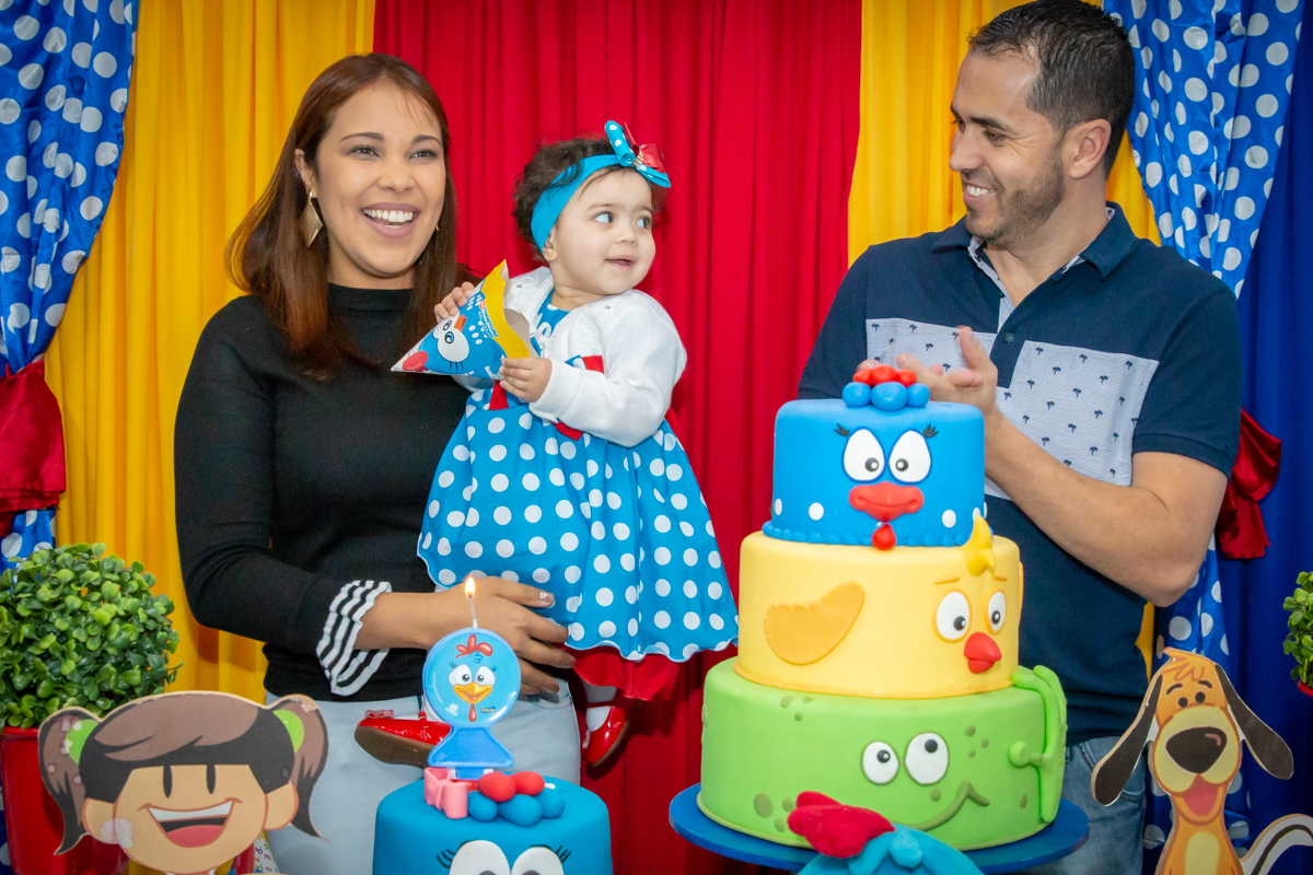 MENINA com seus PAIS cantando PARABÉNS em decoração tema GALINHA PINTADINHA no click do FOTÓGRAFO de FESTA INFANTIL em SÃO PAULO, SP em uma imagem colorida