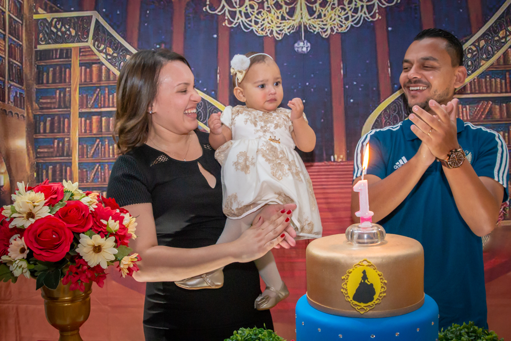 MENINA com seus PAIS cantando PARABÉNS em frente a decoração tema a BELA e a FERA no click do FOTÓGRAFO de FESTA INFANTIL em SÃO PAULO, SP em uma imagem colorida