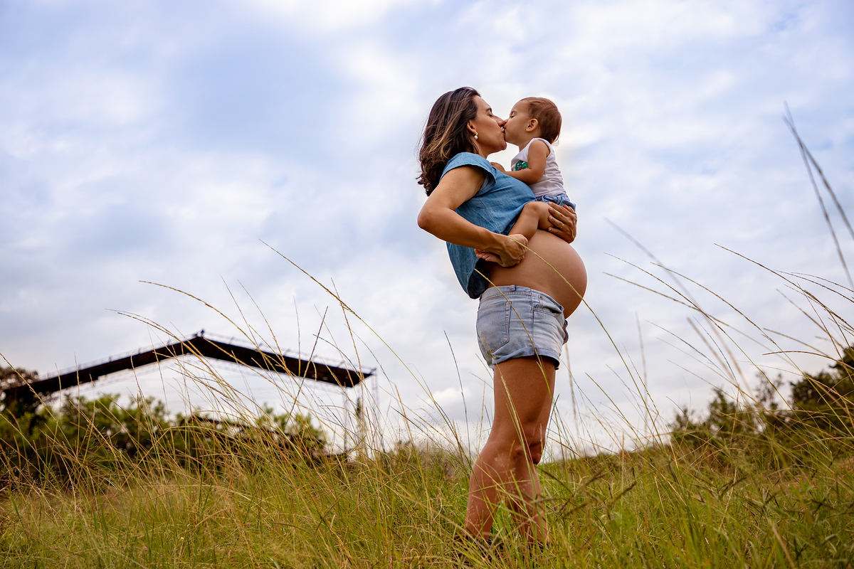 Mulher GRÁVIDA com a BARRIGA de fora, posando em ENSAIO GESTANTE com a FILHA em um SÍTIO, em click do FOTÓGRAFO de GESTANTE.