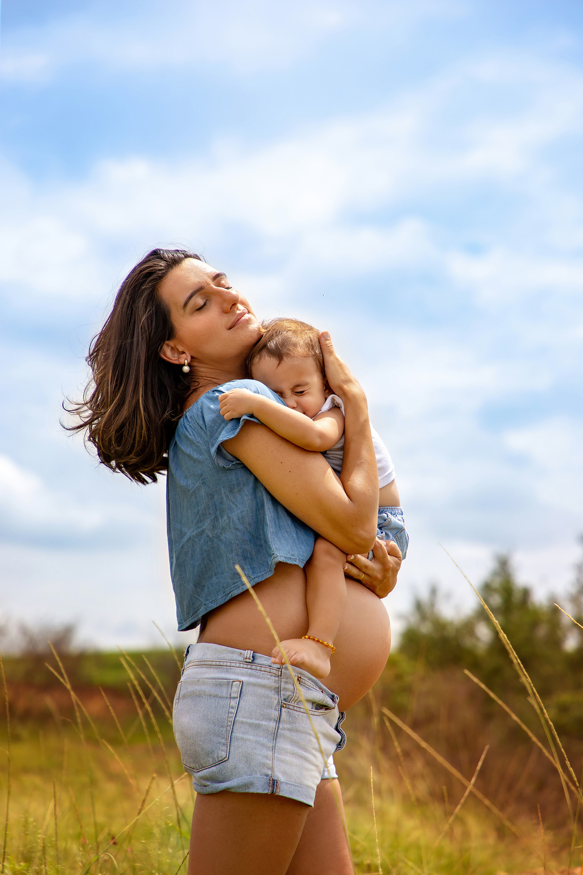 Mulher GRÁVIDA com a BARRIGA de fora, posando em ENSAIO GESTANTE com a FILHA em um SÍTIO, em click do FOTÓGRAFO de GESTANTE.