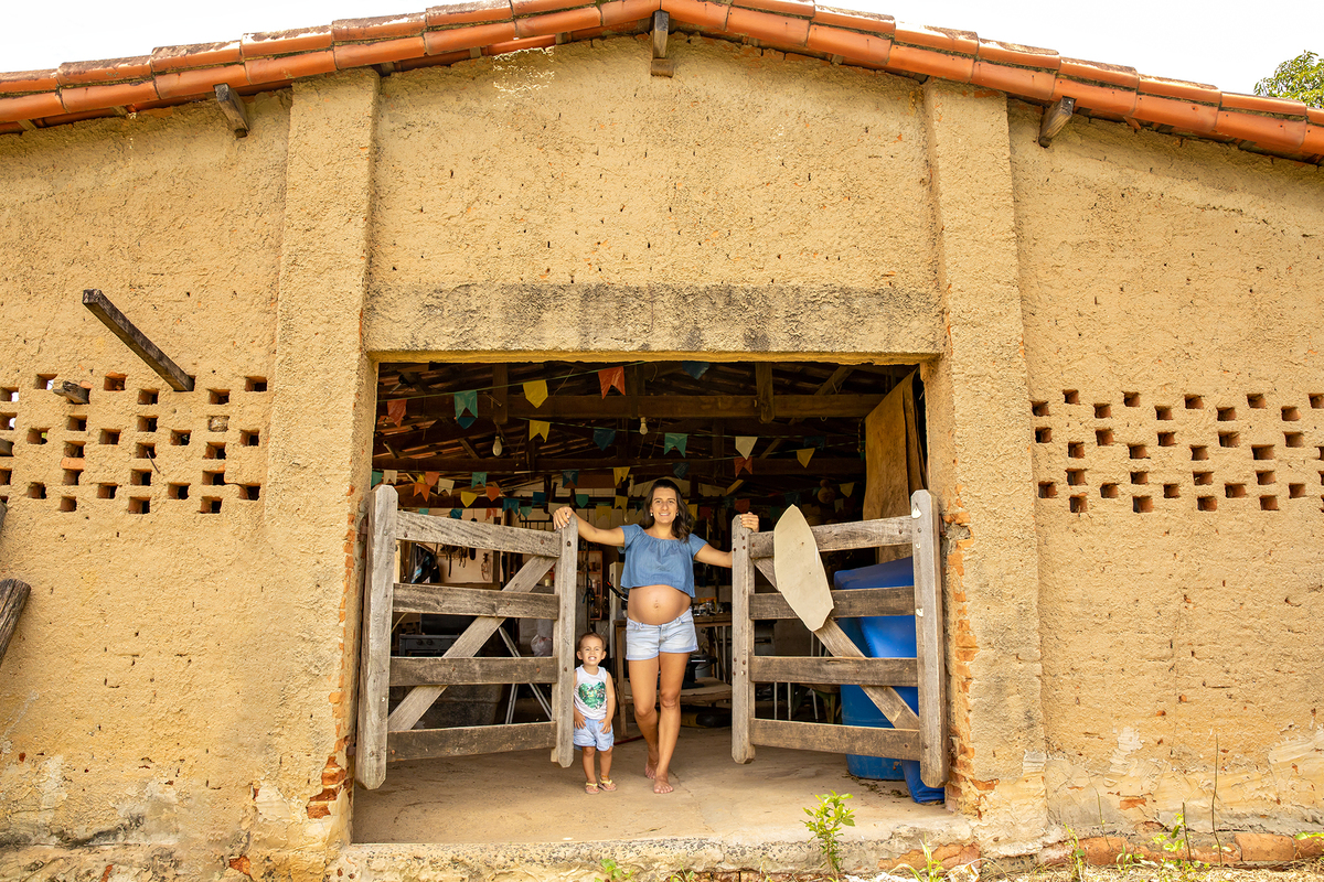 Mulher GRÁVIDA com a BARRIGA de fora, posando em ENSAIO GESTANTE em um SÍTIO, em click do FOTÓGRAFO de GESTANTE.