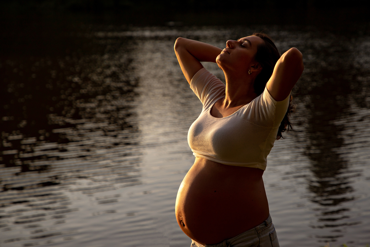 Mulher GRÁVIDA com a BARRIGA de fora, posando em ENSAIO GESTANTE em um SÍTIO, em click do FOTÓGRAFO de GESTANTE.