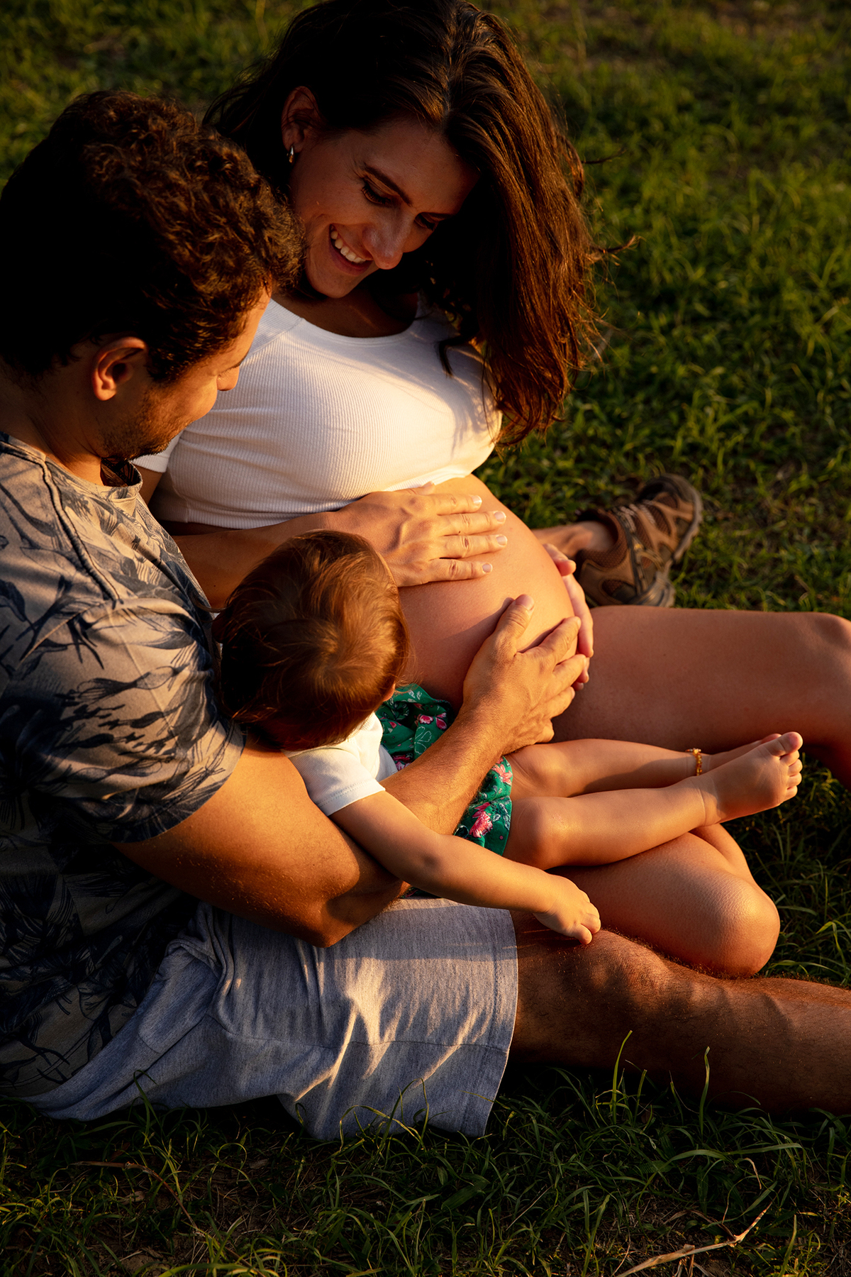 Mulher GRÁVIDA com a BARRIGA de fora, posando com o MARIDO e a FILHA em ENSAIO GESTANTE em um SÍTIO no POR do SOL, em click do FOTÓGRAFO de