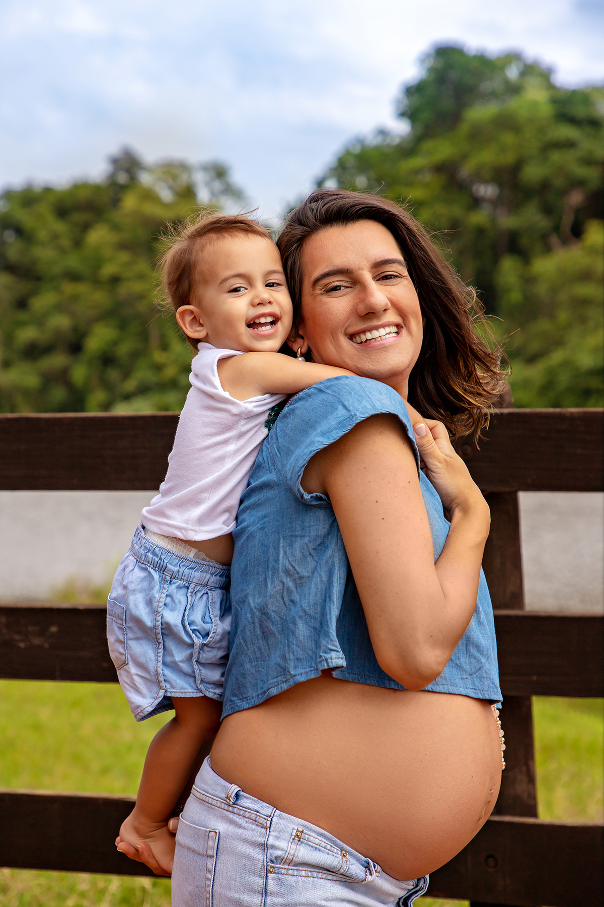 Mulher GRÁVIDA com a BARRIGA de fora, posando em ENSAIO GESTANTE com a FILHA em um SÍTIO, em click do FOTÓGRAFO de GESTANTE.