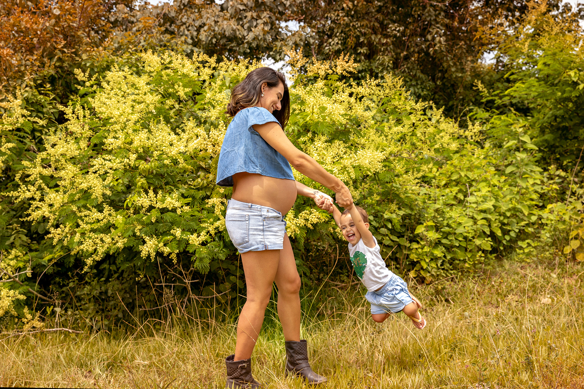 Mulher GRÁVIDA com a BARRIGA de fora, posando em ENSAIO GESTANTE com a FILHA em um SÍTIO, em click do FOTÓGRAFO de GESTANTE.