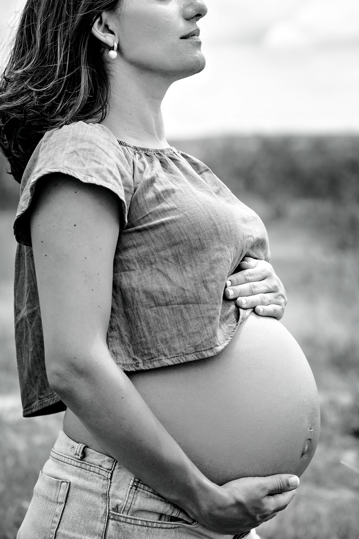 Mulher GRÁVIDA com a BARRIGA de fora, posando em ENSAIO GESTANTE em um SÍTIO, em click do FOTÓGRAFO de GESTANTE.