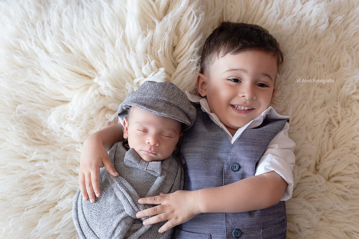 Ensaio Newborn do Gabriel filho mais novo ta Thali Freitas foto com irmãozinho em tons de branco e cinza Gustavo abraçando seu irmãozinho ensaio newborn a domicílio zona sul de são paulo e Osasco estúdio especializado