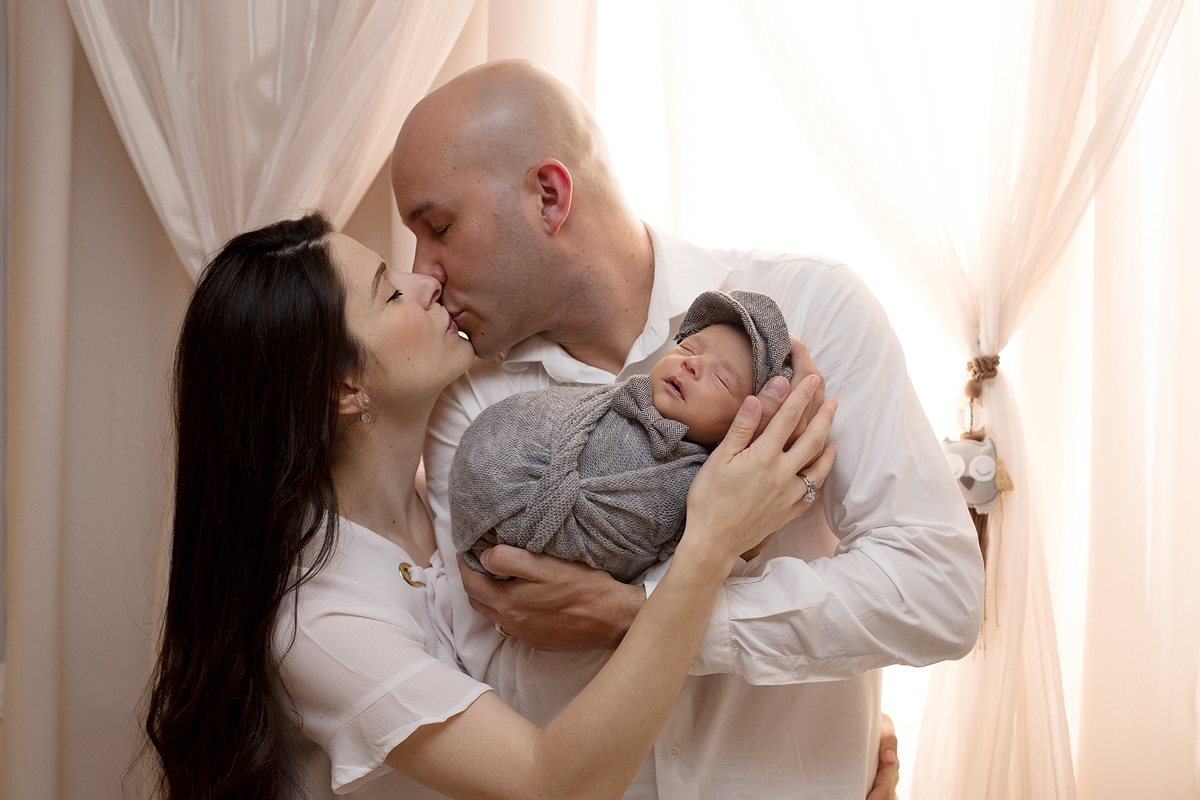 Ensaio newborn em casa ensaio newborn lifestyle foto com pais, bebê recem nascido no colo dos pais papais se beijando ensaio em casa Zona Sul de São Paulo SP