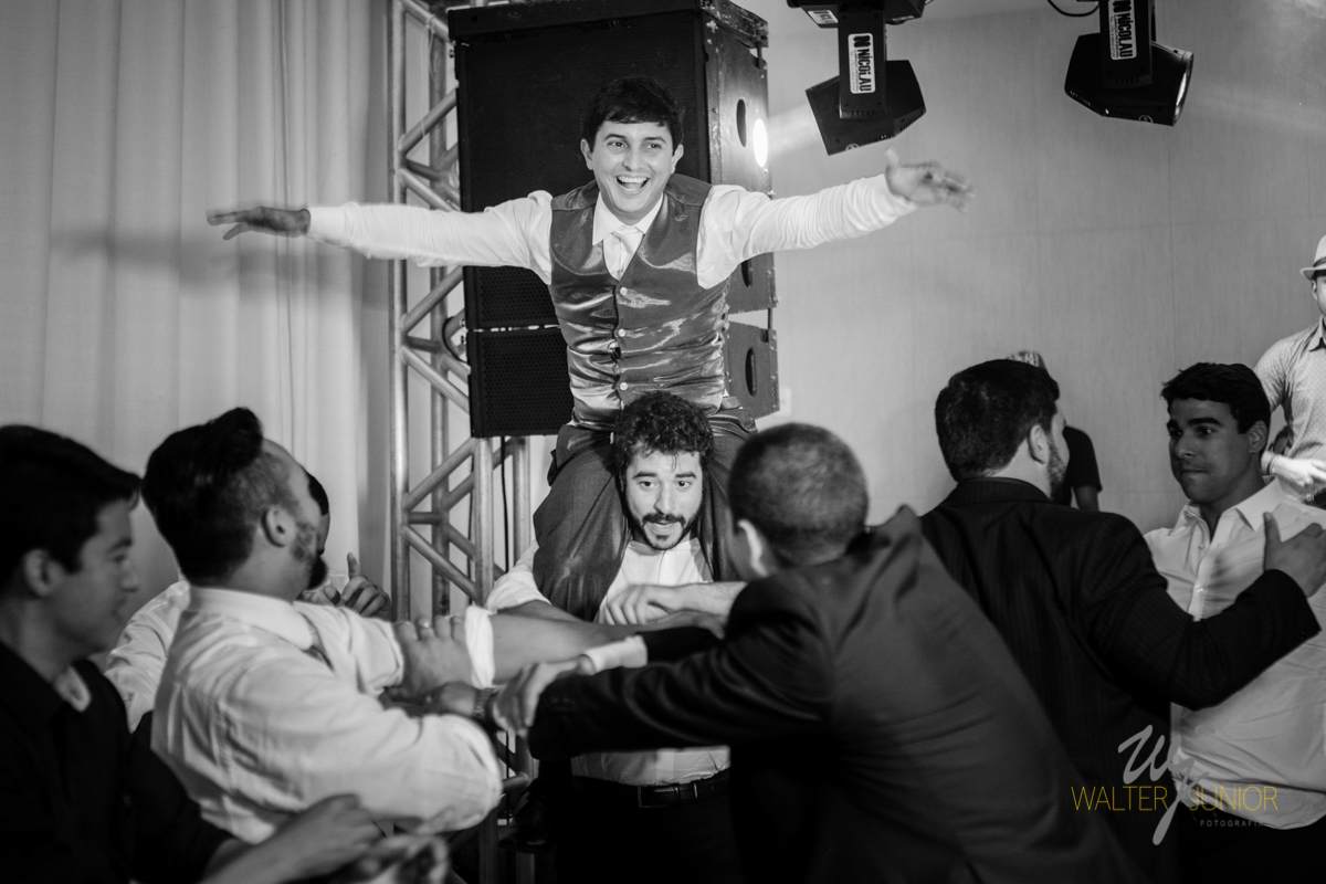 noivo sendo carregado pelos os colegas na noite do casamento 