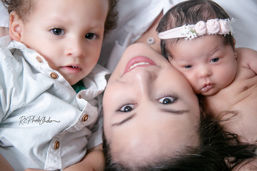 Fot de menina deitada com mamãe e irmão