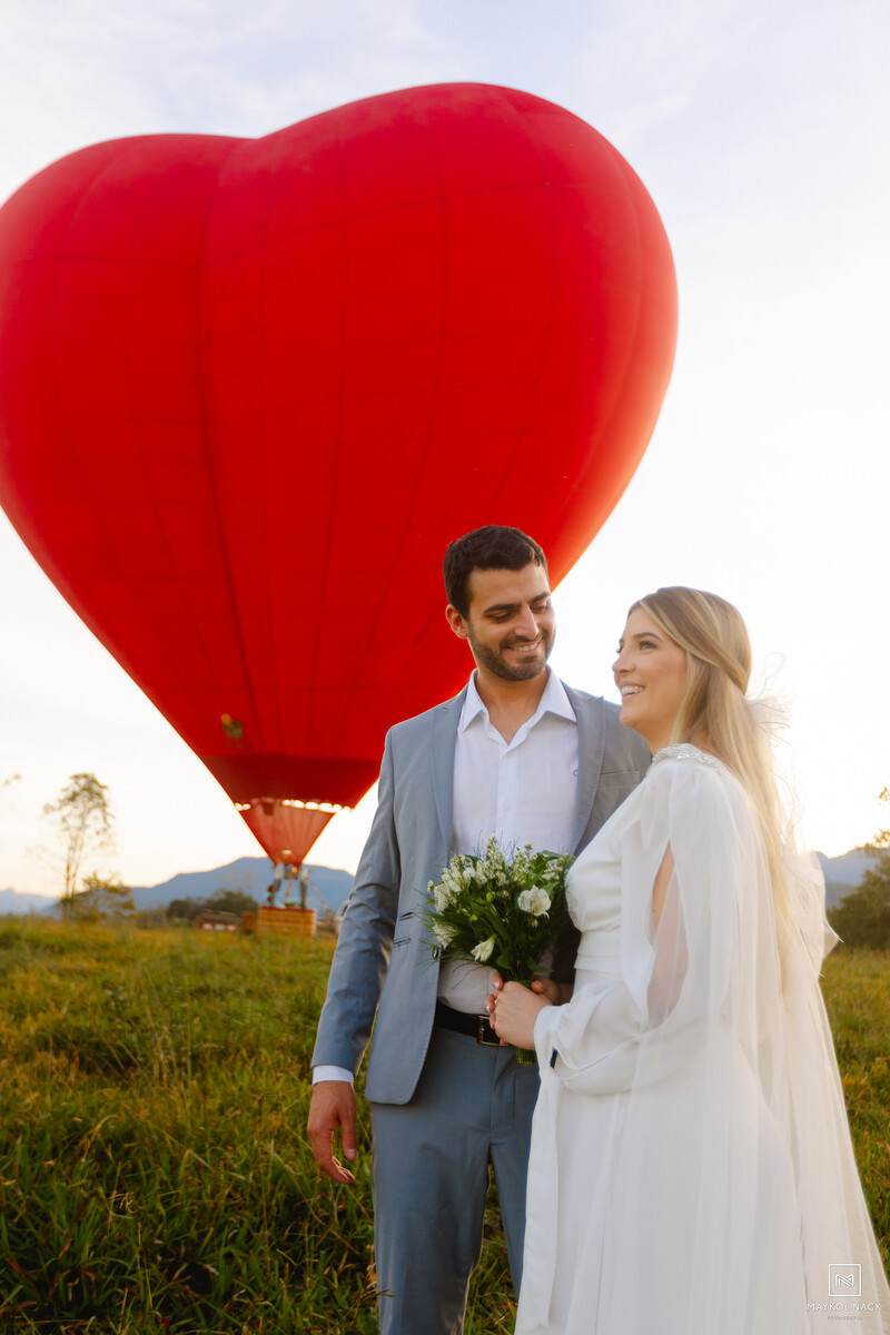 casal sorrindo com balão de coração