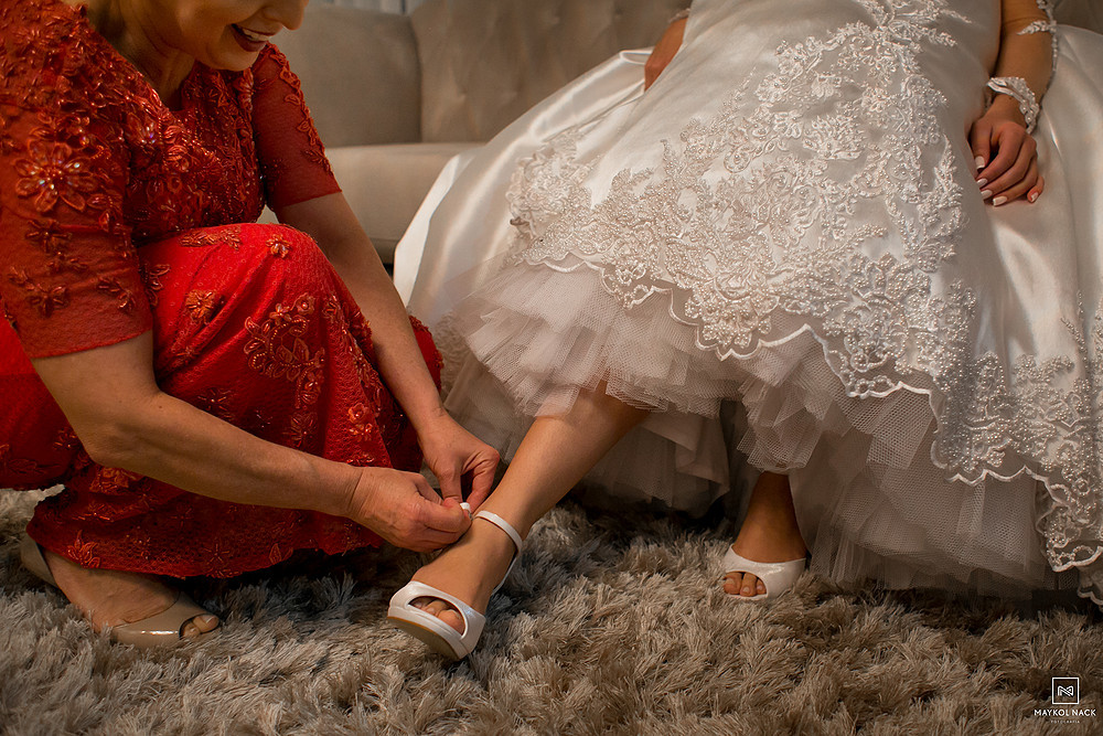 mãe ajudando a noiva a colocar sapato