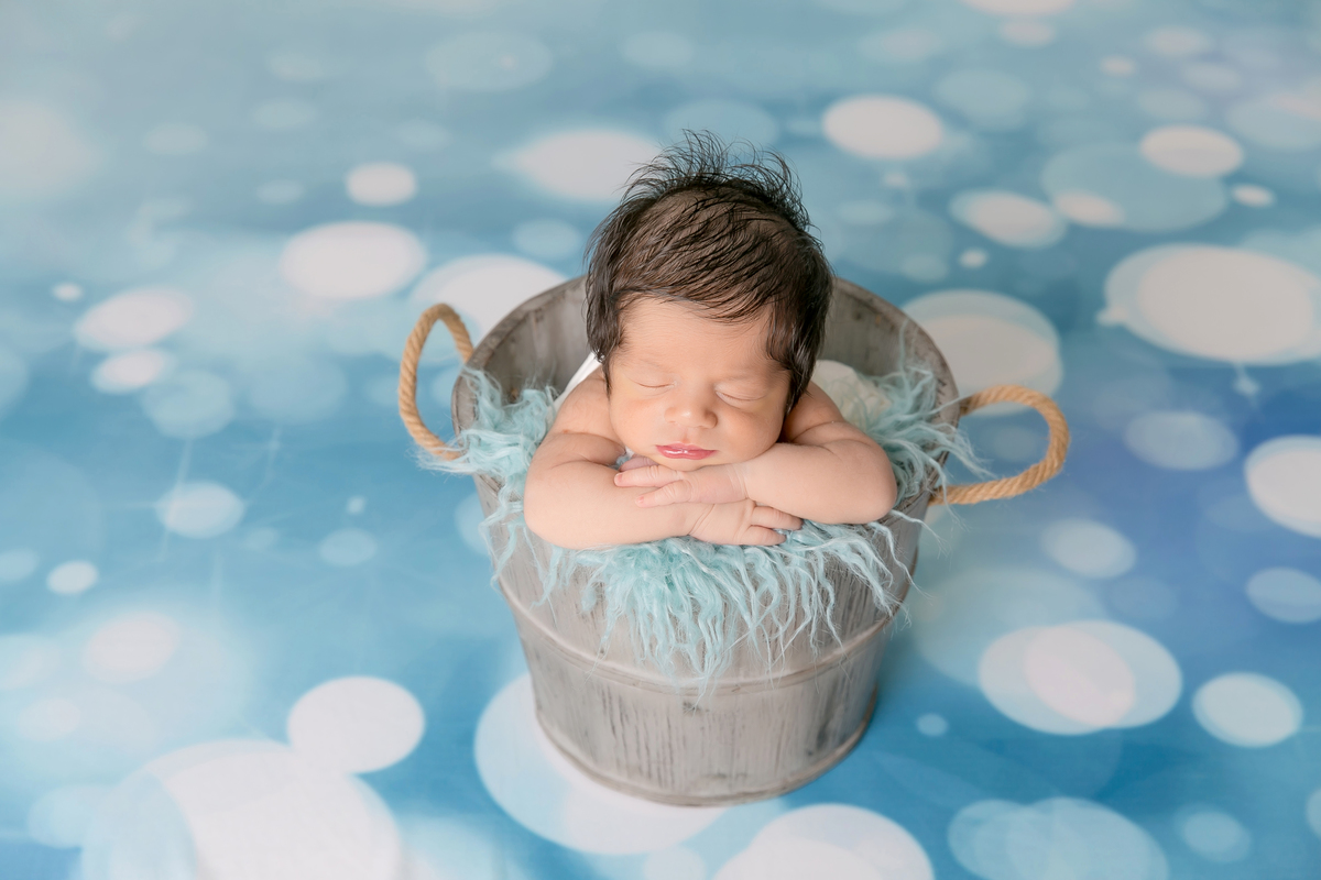 bebe no cestinho, pose do bracinho , fundo azul , desfoque de fundo, bebe cabeludo newborn de menino, newborn em santos, fotografos da baixada santinta. fotografia newborn