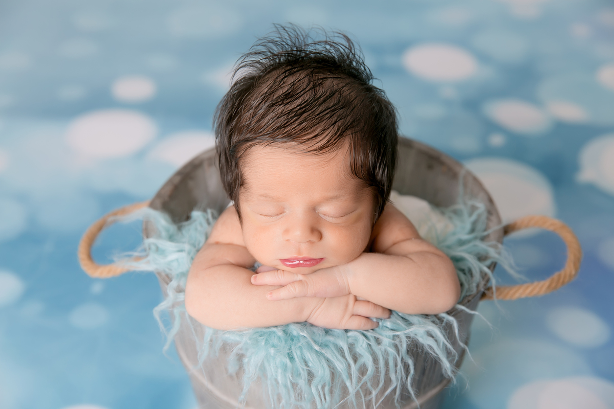 bebe no cestinho, pose do bracinho , fundo azul , desfoque de fundo, bebe cabeludo newborn de menino, newborn em santos, fotografos da baixada santinta. fotografia newborn