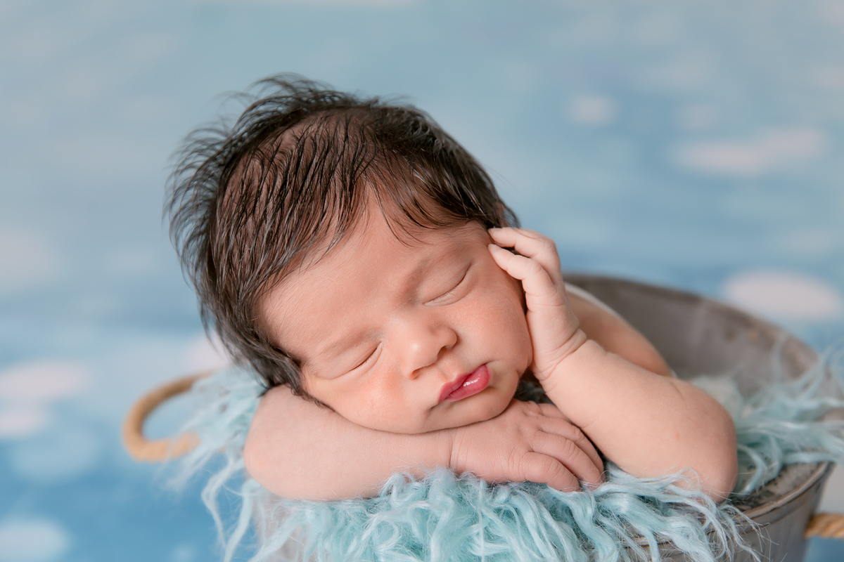 bebe no cestinho, pose do bracinho , fundo azul , desfoque de fundo, bebe cabeludo newborn de menino, newborn em santos, fotografos da baixada santinta. fotografia newborn