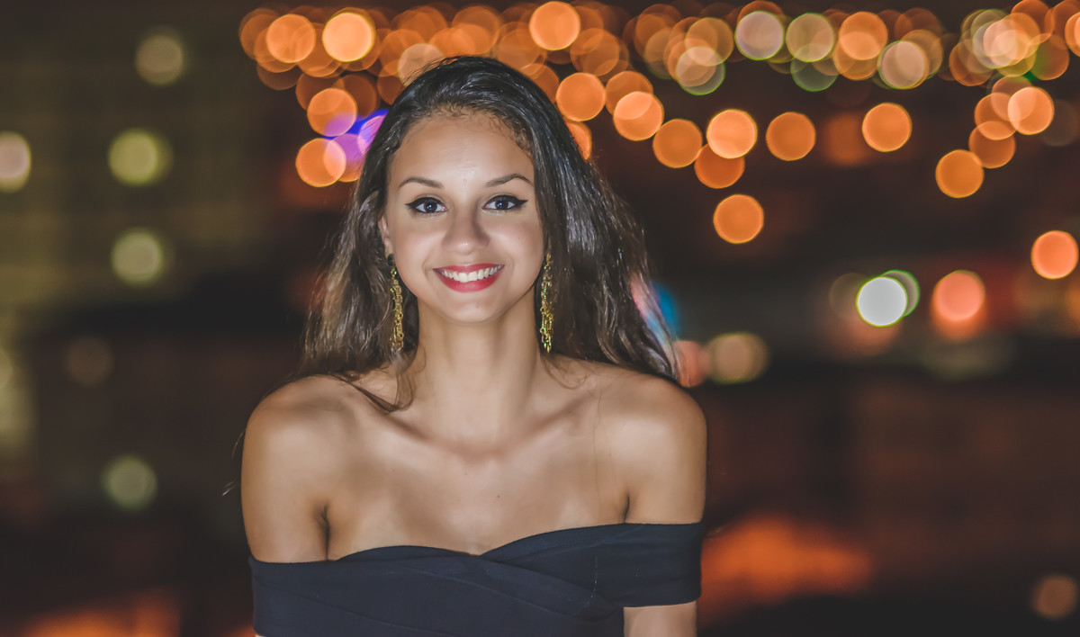Fotografia da debutante sorrindo no alto do prédio com efeito de luzes ao  fundo - ensaio de 15 anos - Cia P&B - Fotografia - Praia Grande
