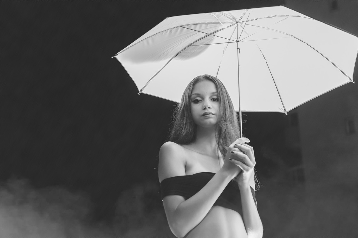 Fotografia da debutante segurando uma sombrinha iluminada com efeito de fumaça ao fundo - ensaio de 15 anos - Cia P&B Fotografia - Praia Grande