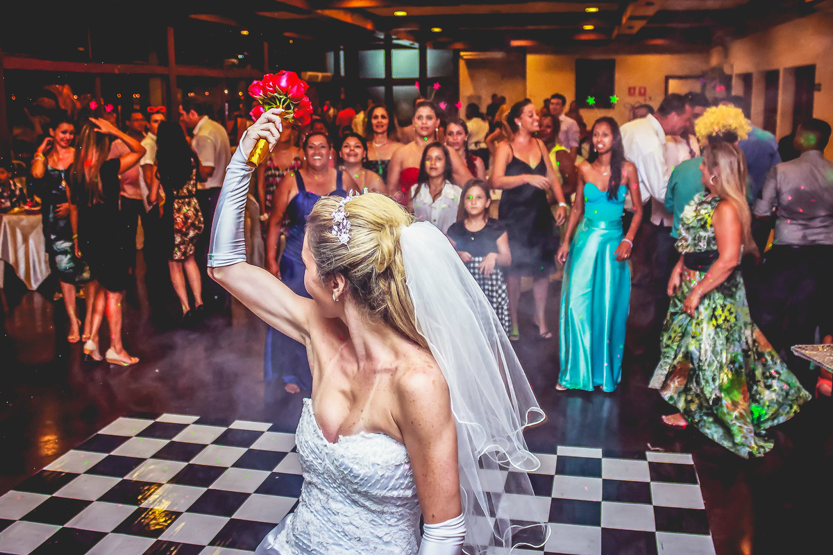 Fotografia da noiva jogando o buquê durante a festa de casamento no Iate Clube de Praia Grande - Cia P&B - Fotografia 