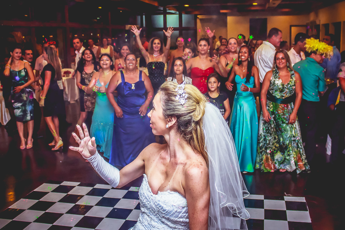 Fotografia da noiva jogando o buquê e das convidadas esperando para pegar durante a festa de casamento no Iate Clube de Praia Grande - Cia P&B - Fotografia 