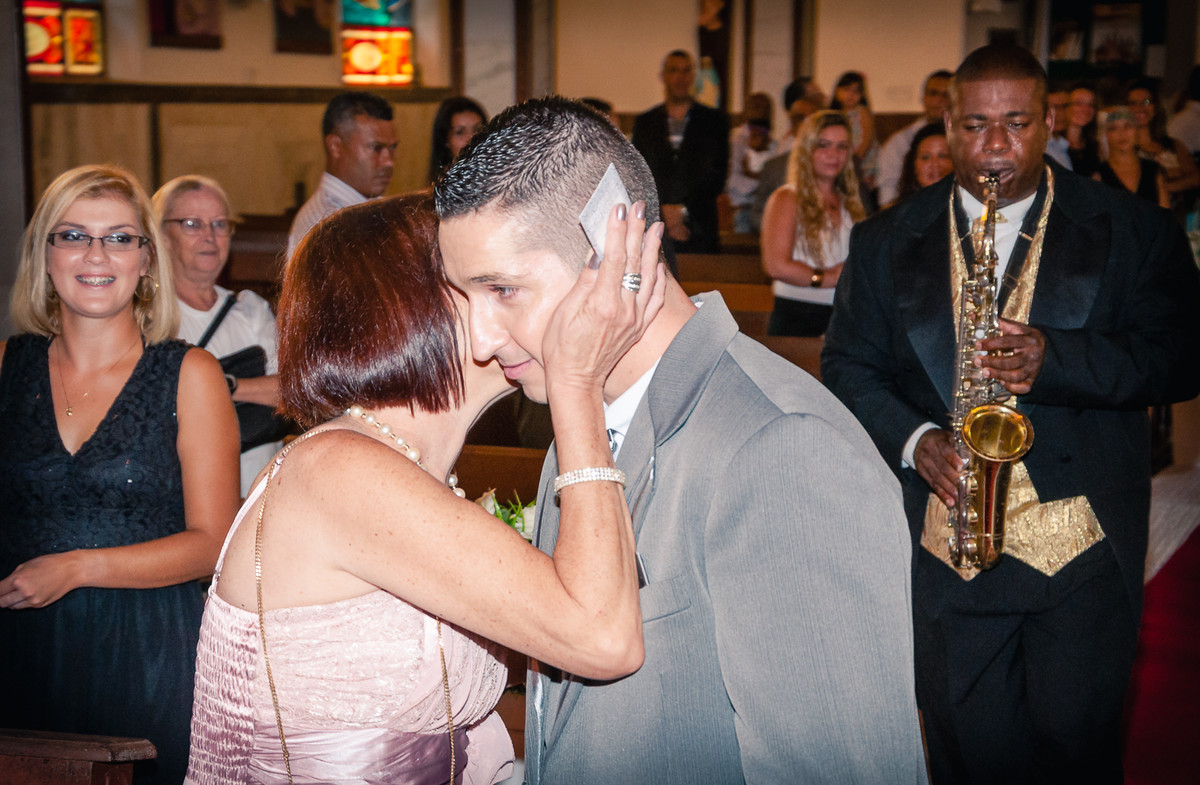 Fotografia do beijo da mãe no noivo durante o casamento na Igreja Paróquia Nossa Senhora Aparecida em Mongaguá - Cia P&B - Fotografia