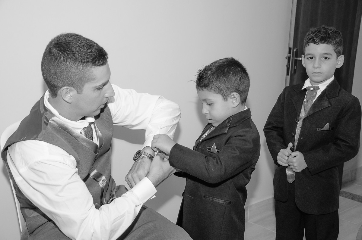 Fotografia do noivo com seu filho abotoando a manga da camisa durante o making of antes do casamento - Praia Grande - Cia P&B - Fotografia