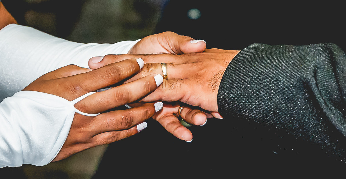 Fotografia da noiva colocando a aliança no dedo do noivo durante o casamento no buffet Espaço Free em Praia Grande - Cia P&B - Fotografia