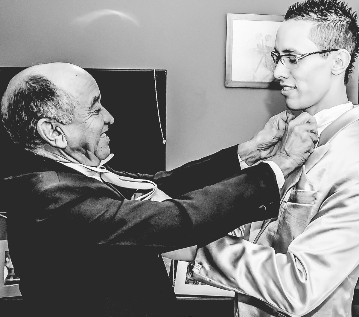 Fotografia do pai do noivo arrumando o colarinho da camisa do noivo durante o making of em Mongaguá - Cia P&B - Fotografia 