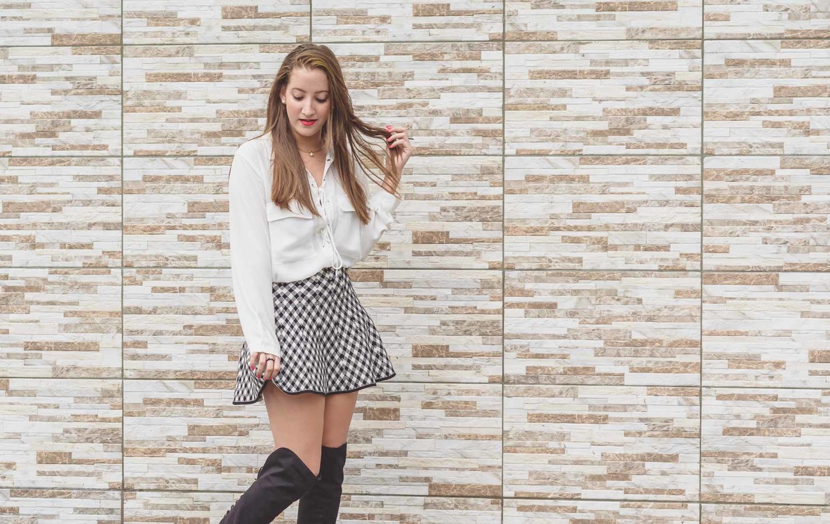 Fotografia da blogueira Fofuras da Ka com saia preta e branca segurando o cabelo durante ensaio fotográfico em Itanhaém - Cia P&B - Fotografia 