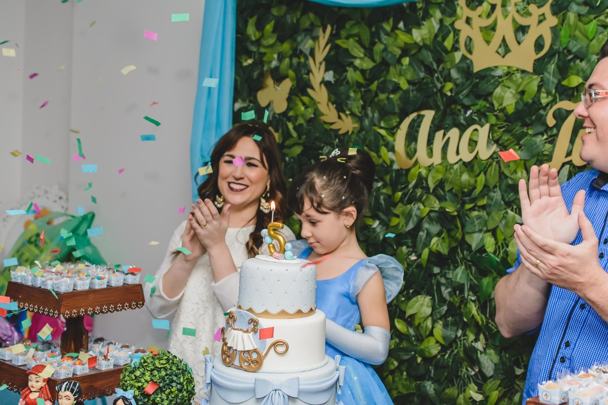 Fotografia da Ana Julia e seus pais cantando parabéns com chuva de papel colorido durante o aniversário infantil em São Paulo - Cia P&B - Fotografia