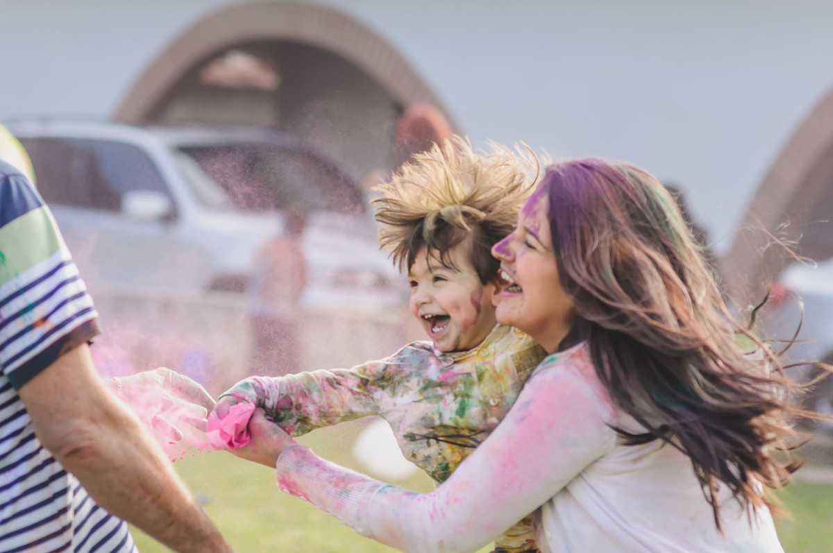 Fotografia da madrinha com o Enzo jogando tinta durante o ensaio infantil paint em Mongaguá - Cia P&B -Fotografia