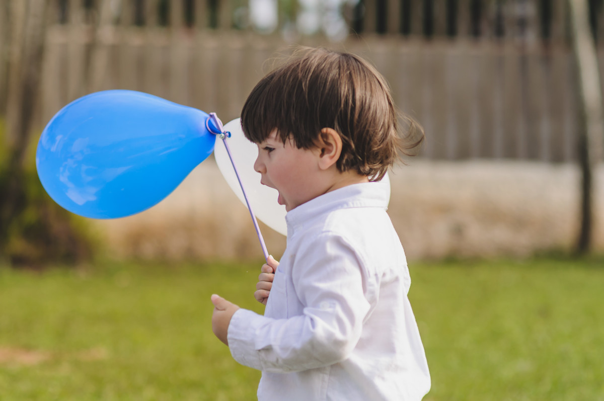 Foto do Enzo segurando balões durante seu ensaio infantil em Mongaguá -  Cia P&B - Fotografia 