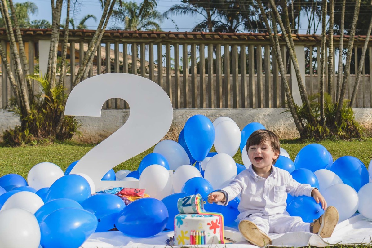 Foto do Enzo com bolo e balões e o número 2 em seu ensaio infantil paint em Mongaguá -  Cia P&B - Fotografia