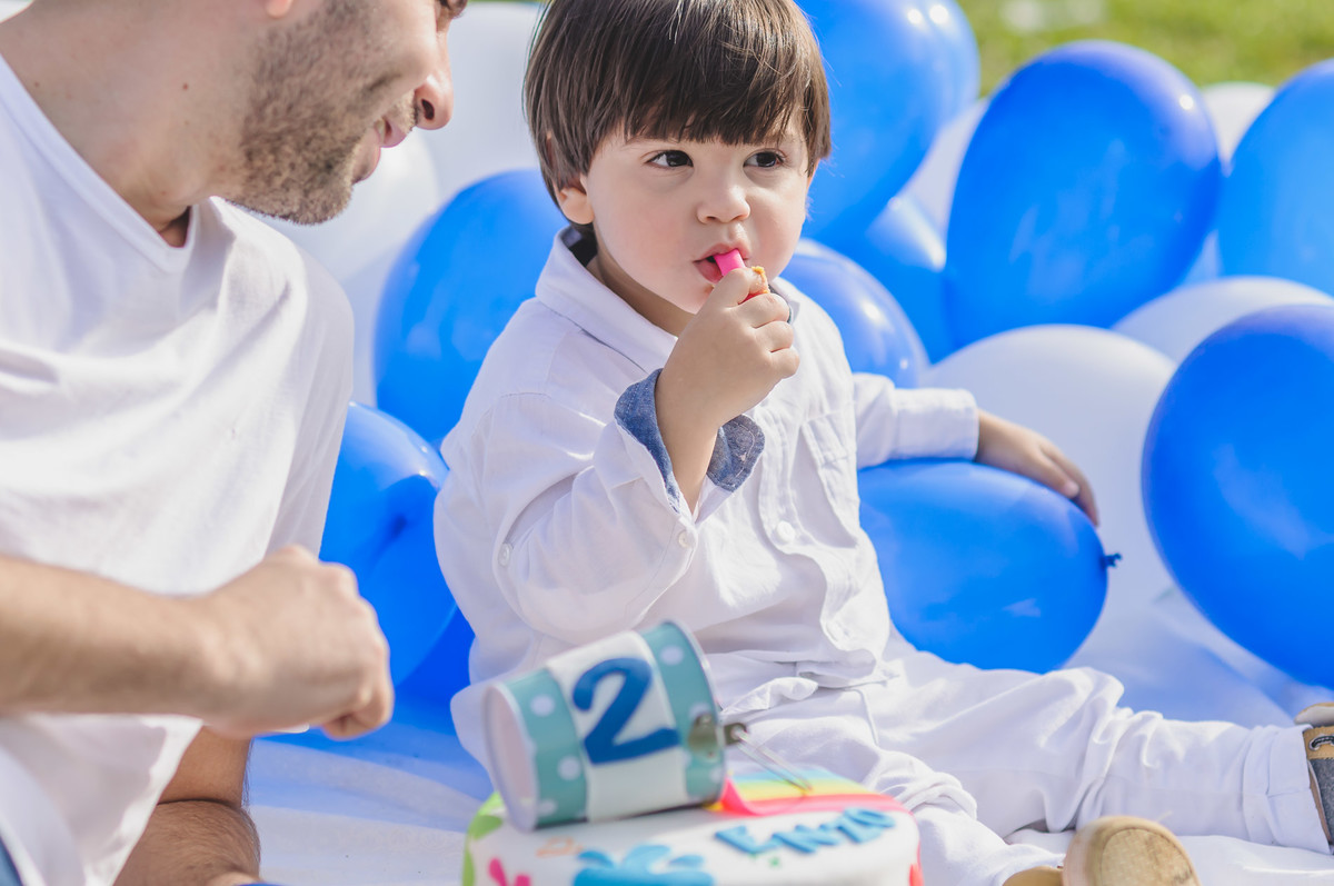 Foto do Enzo comendo um doce do bolo durante seu ensaio infantil paint em Mongaguá - Cia P&B - Fotografia