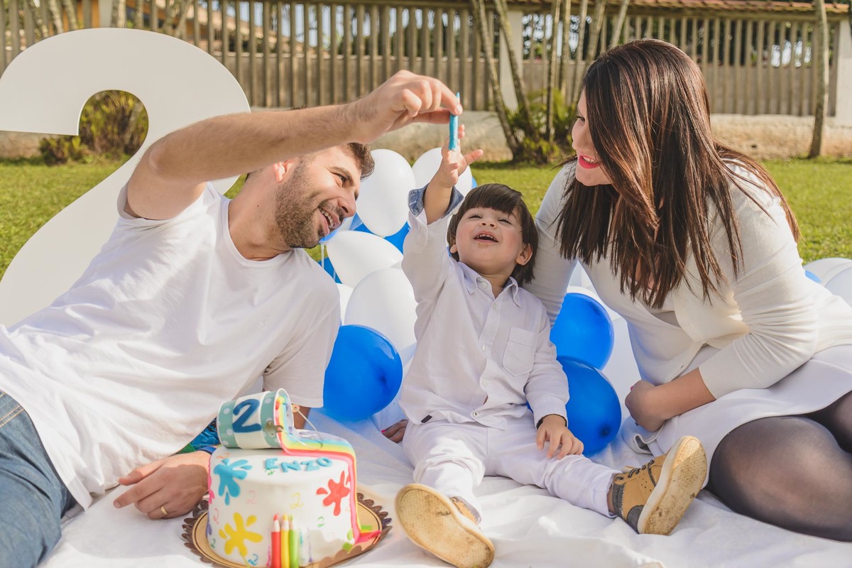 Foto do Enzo com seus pais brincando com o bolo no ensaio infantil paint em Mongaguá - Cia P&B - Fotografia 