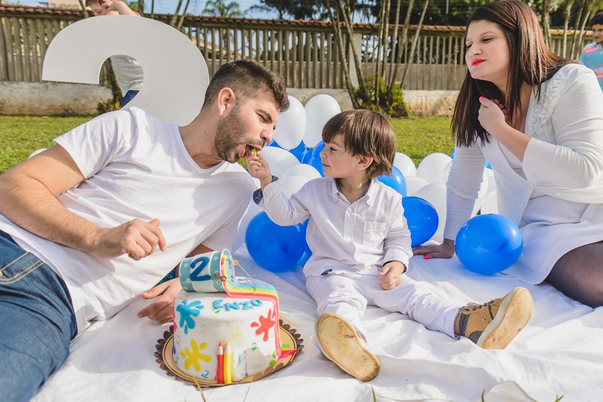 Foto do Enzo dando doce na boca do seu pai durante o ensaio infantil paint em Mongaguá - Cia P&B - Fotografia 
