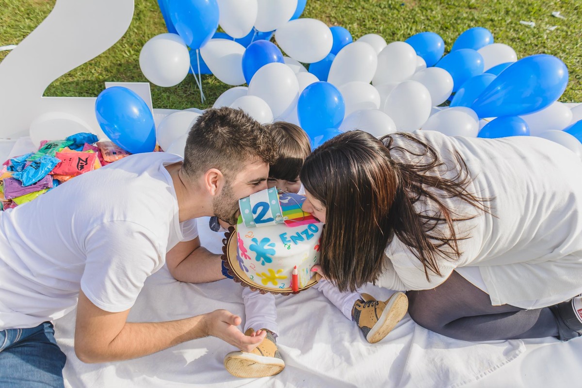 Foto do Enzo com os pais mordendo o bolo durante o ensaio infantil paint em Mongaguá  - Cia P&B - Fotografia