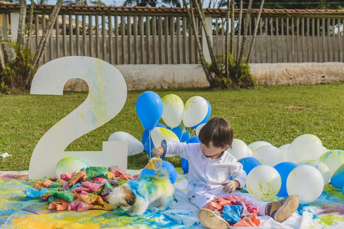 Foto do enzo e sua cachorrinha com as tintas em pó durante o ensaio infantil paint em Mongaguá - Cia P&B - Fotografia